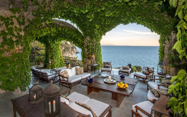 terrace with white furniture and a wooden tableoverlooking the sea