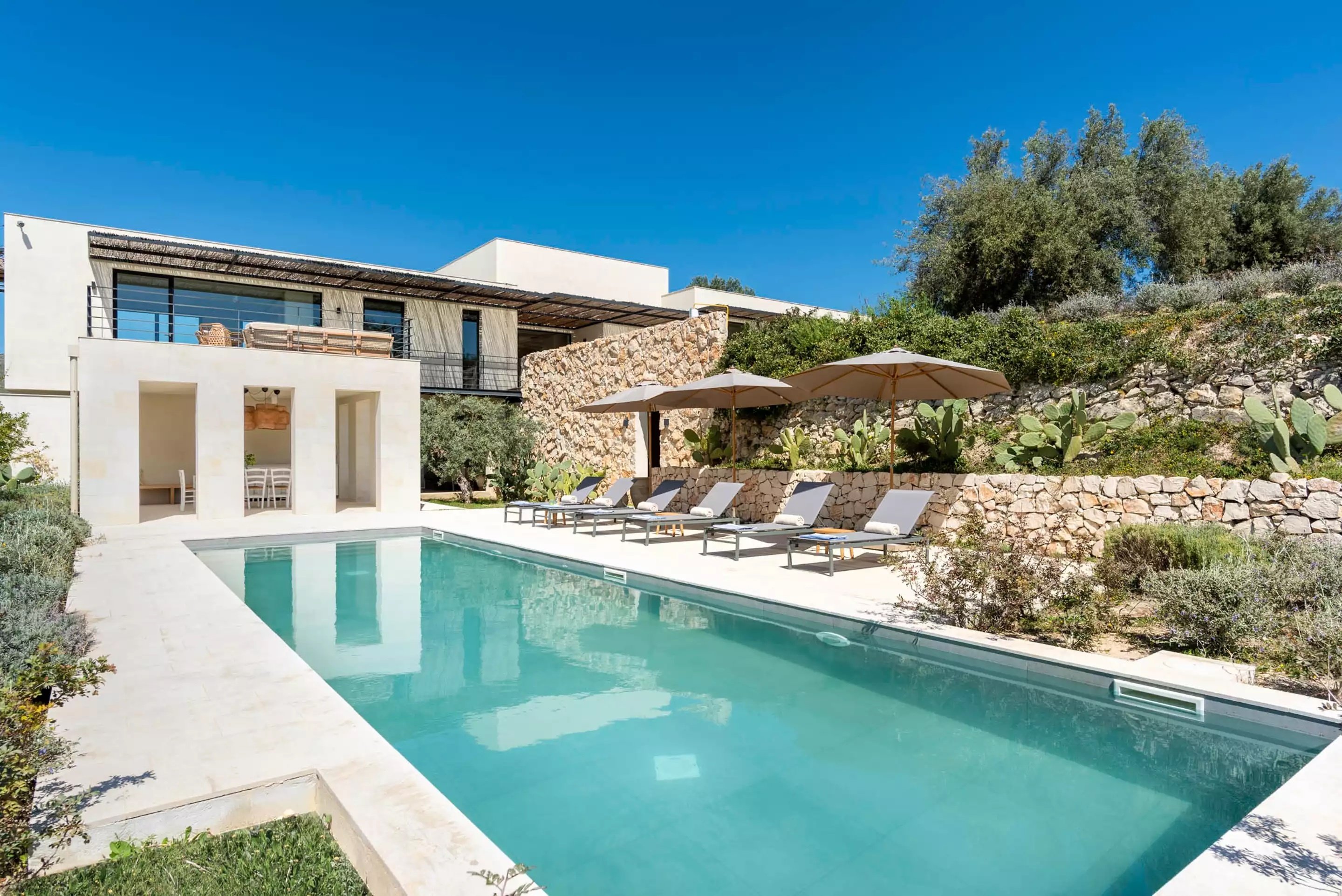 villa pool with lounge chairs and umbrellas surrounded by nature