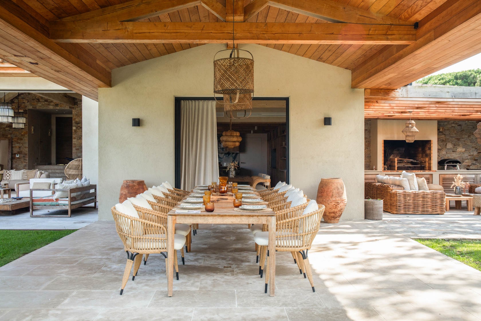 terrasse-exterieure-avec-table-a-manger-dressee-et-chaises-en-bois-lampes-en-osier-plafond-en-bois-et-salons-exterieurs-sur-les-cotes