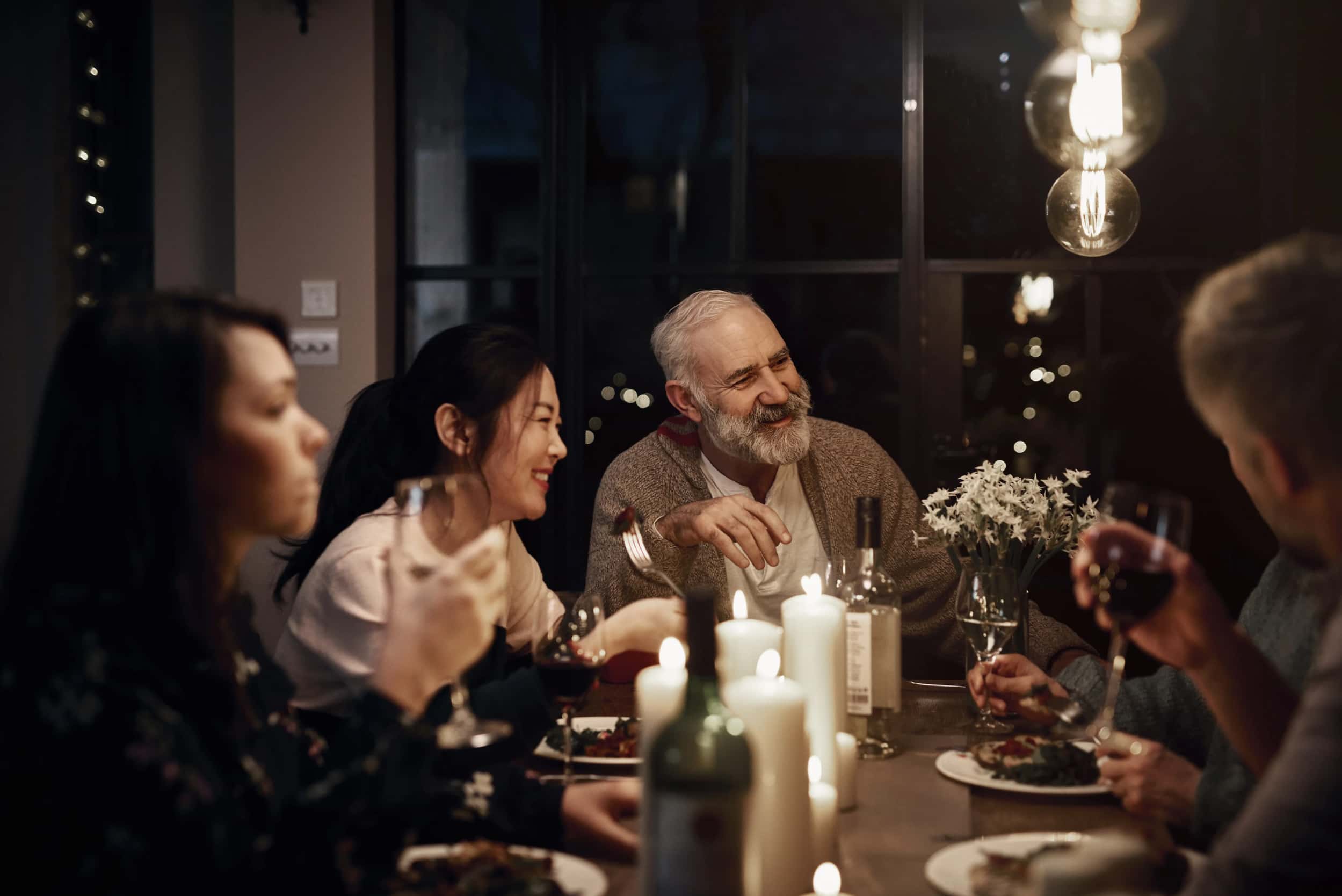 Christmas-dinner-with-an-older-man-two-women-and-two-men-sat-around-a-filled-table