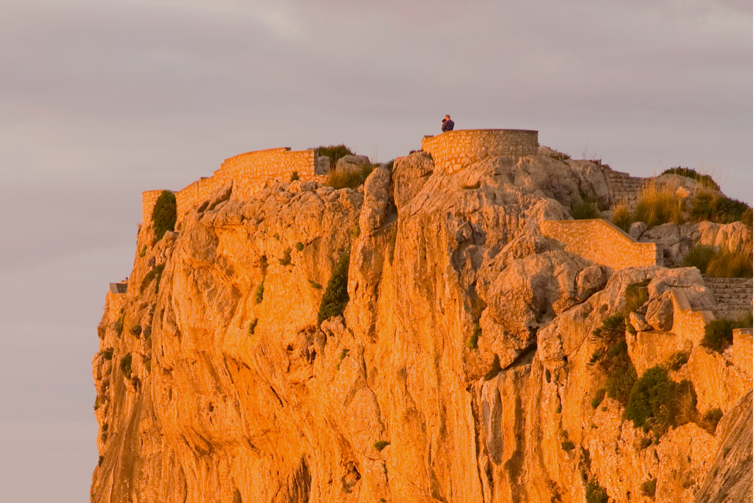 Man taking a photo from atop of rocky cliff in Ibiza
