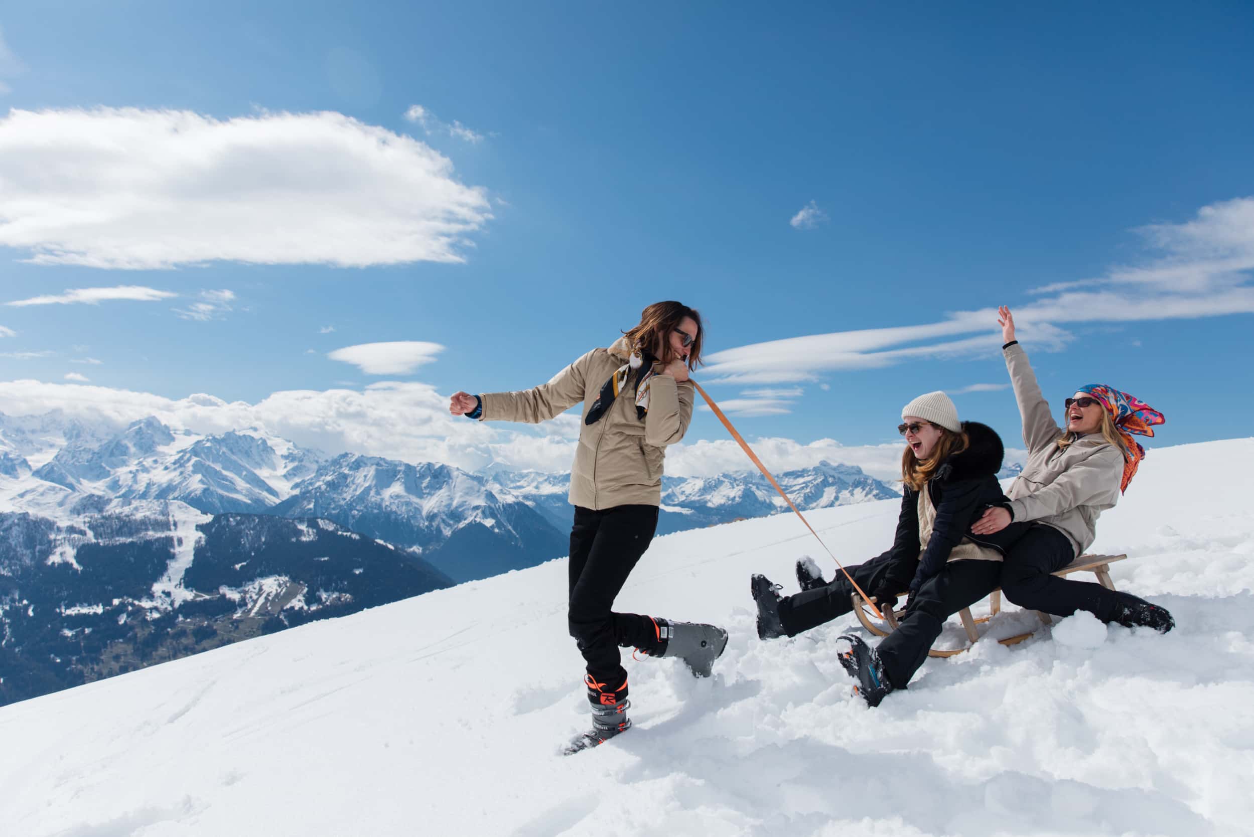 Two-women-being-pulled-along-on-a-sled-by-a-woman-all-laughing