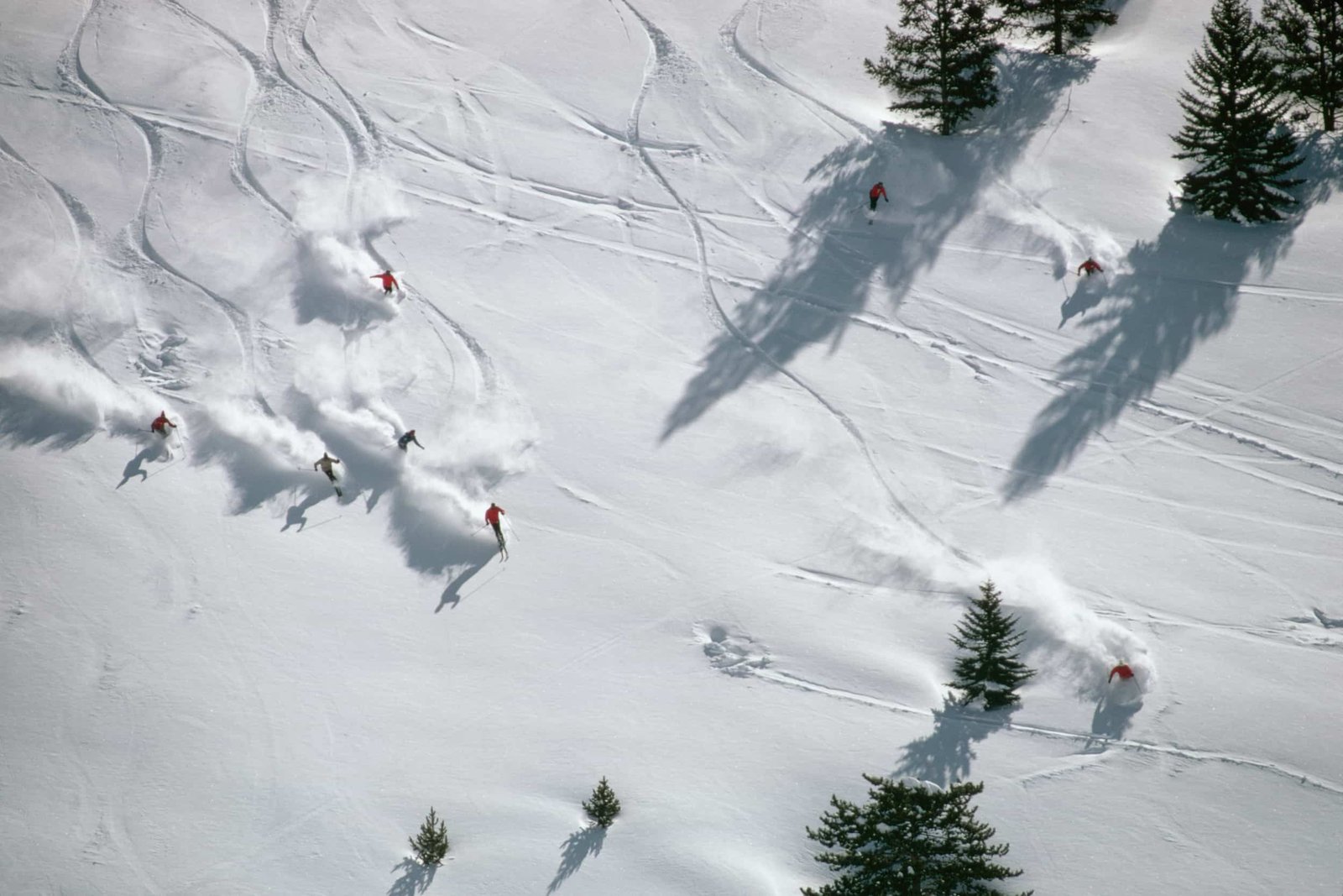 Skieurs traçant leurs courbes dans la poudreuse, vus du ciel