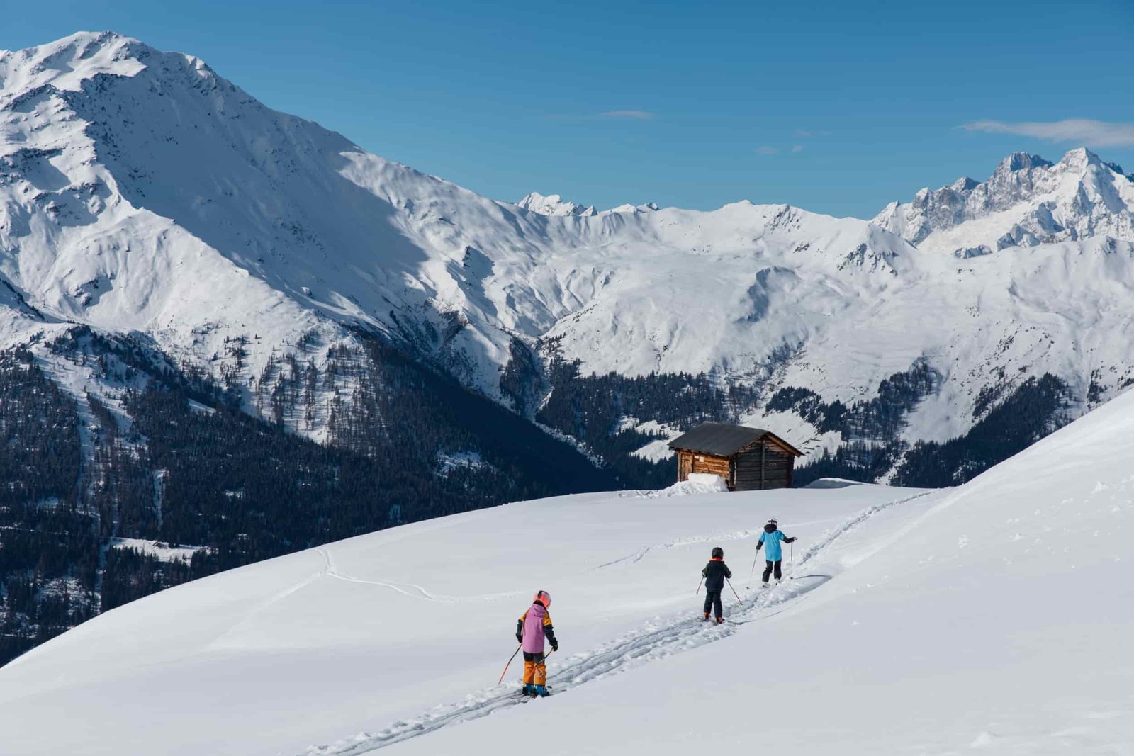 Enfants à ski sur une pente douce face aux sommets enneigés