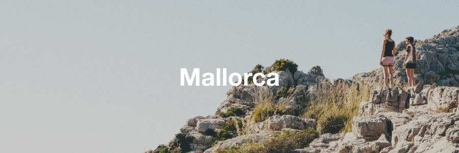 people standing on rocks in hiking gear with the word Mallorca written on top in white