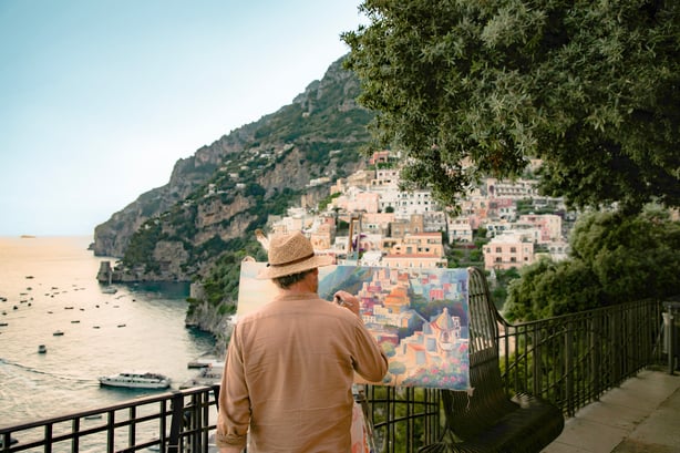 man painting positano from a distance