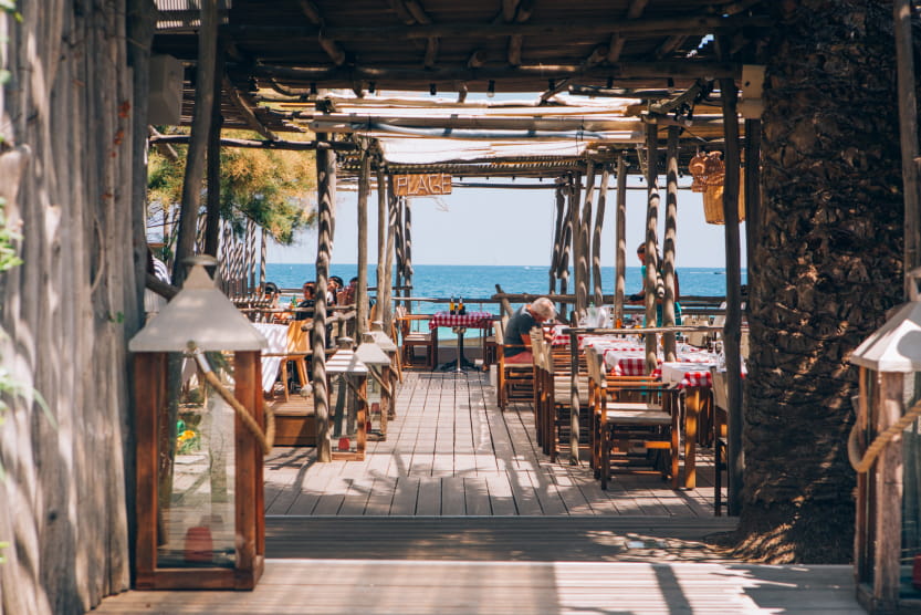 entree-du-nikki-beach-ramatuelle-restaurant-et-club-de-plage-murs-en-bois-table-dressees-mer-en-arriere-plan