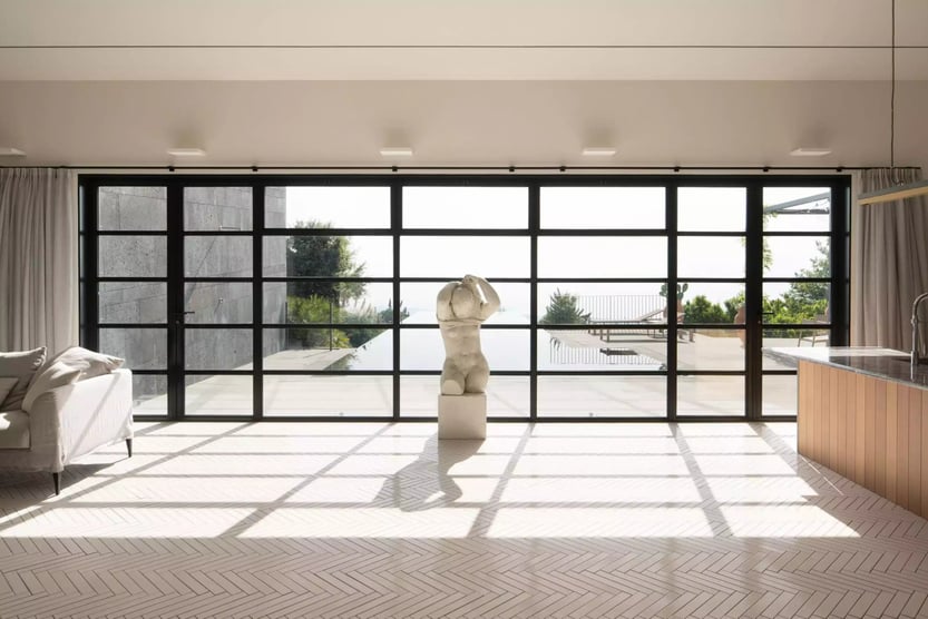 living room and kitchen of villa etna with large window and a marble statue of a man in front of it