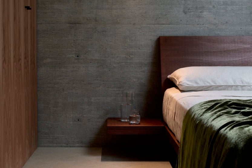 bedroom at Villa Primordiale with concrete and wood walls and plush green bedding