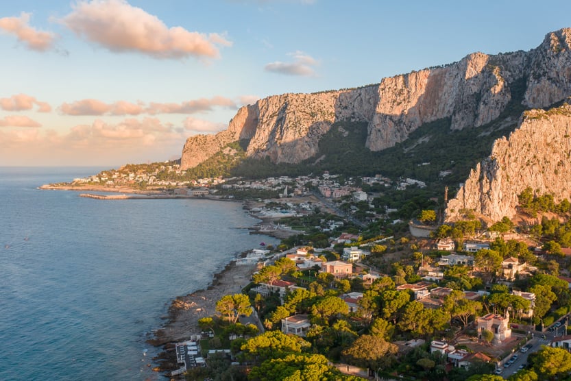 Aerial view of coastal village and cliffs at sunset in Sicily