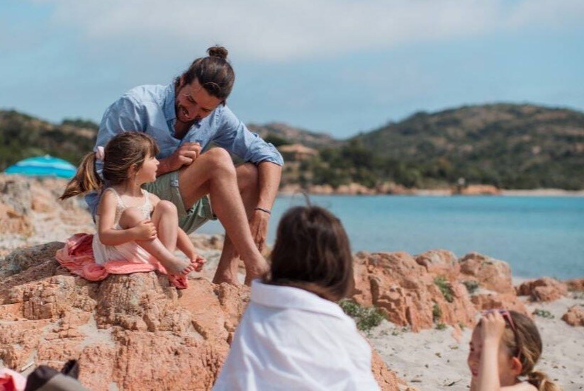 family at the beach sitting on rocks