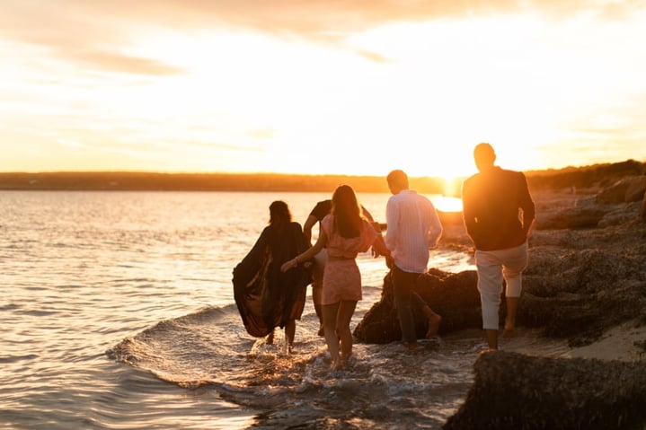 groupe-d-amis-se-promenant-le-long-de-la-mer-au-coucher-du-soleil-sur-une-plage-d-ibiza-en-septembre