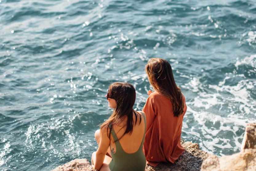 girls sitting on a rock by the sea