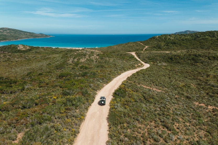 vue-drone-sur-une-jeep-remontant-un-sentier-de-terre-en-direction-de-la-mer