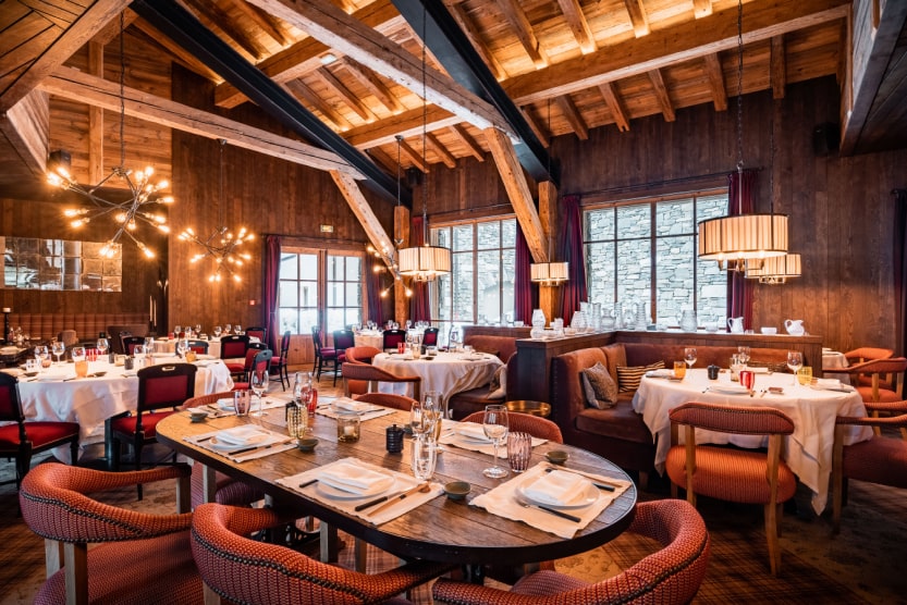 inside-of-a-typical-mountain-restaurant-red-velvet-chairs-and-tables-set-with-hanging-lights-from-wooden-ceiling