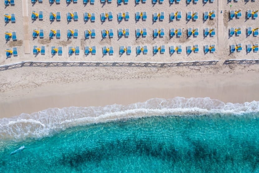 vue-en-drone-d-une-plage-en-sicile-avec-la-mer-turquoise-et-une-multitude-de-chaises-longues-alignees
