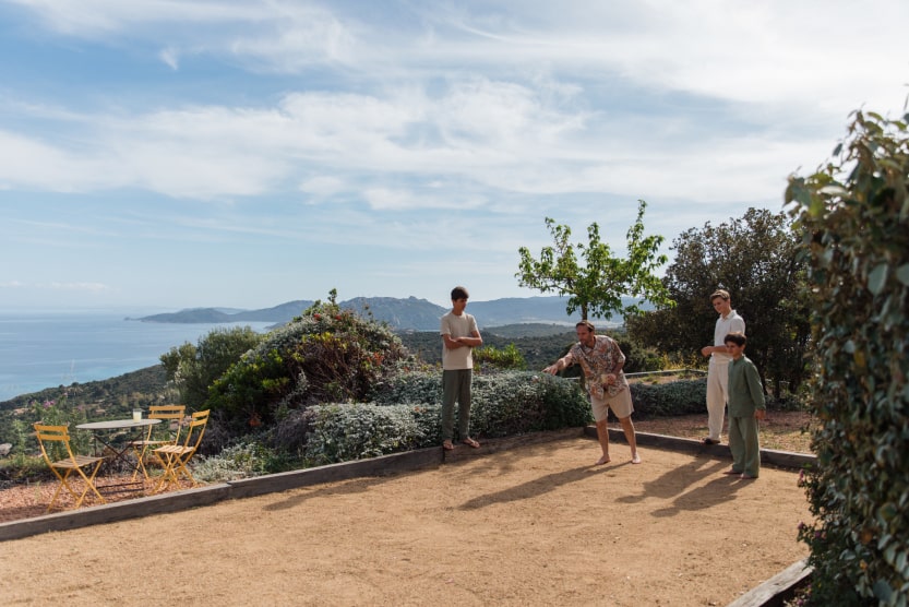 pere-et-ses-fils-jouant-sur-le-terrain-de-petanque-d-une-maisosn-avec-vue-panoramique-sur-la-mer