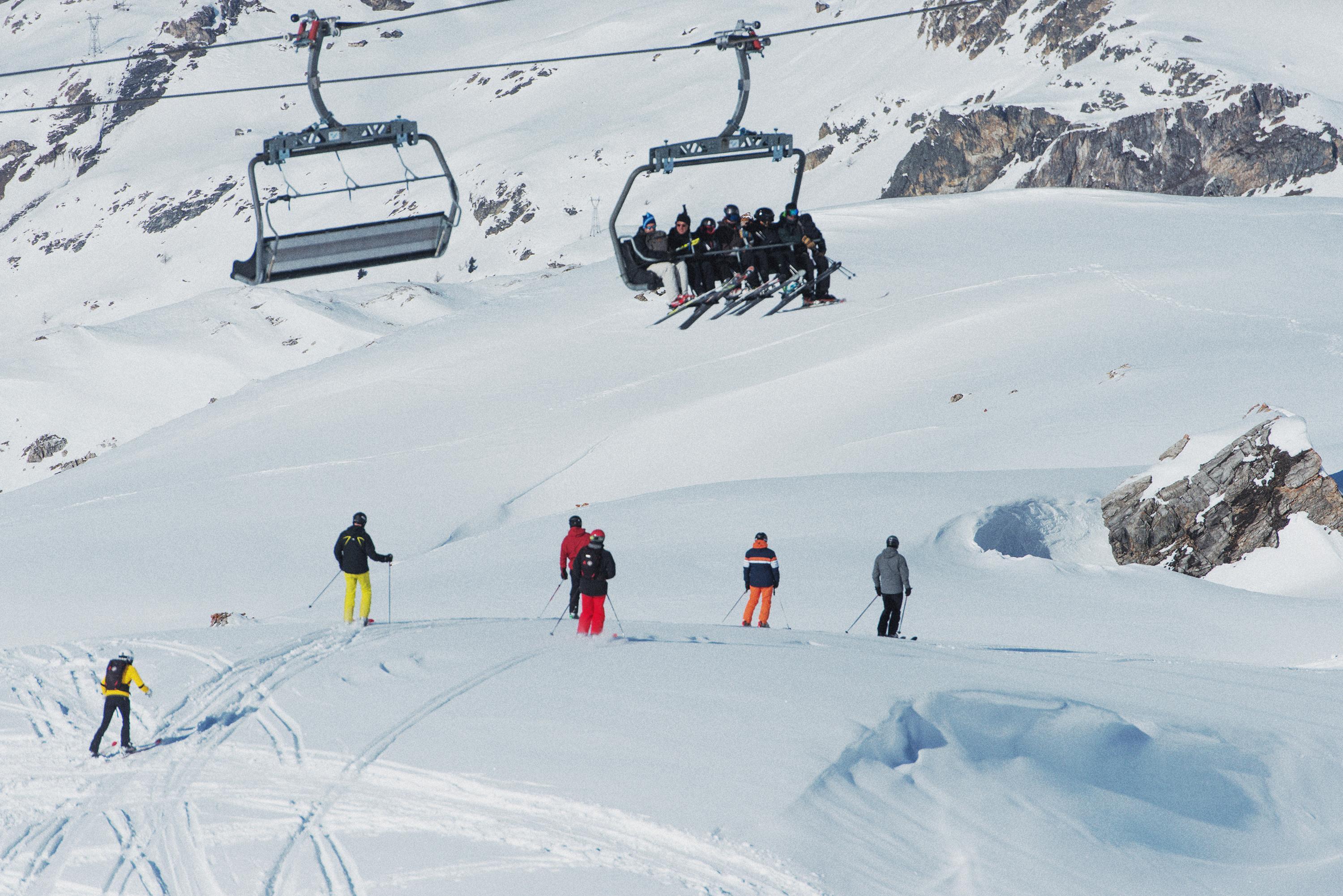 skiiers below a ski lift filled with people