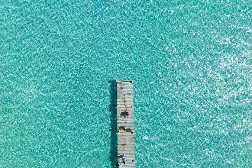 vue-de-drone-d-un-ponton-en-bois-s-avancant-sur-la-mer-turquoise