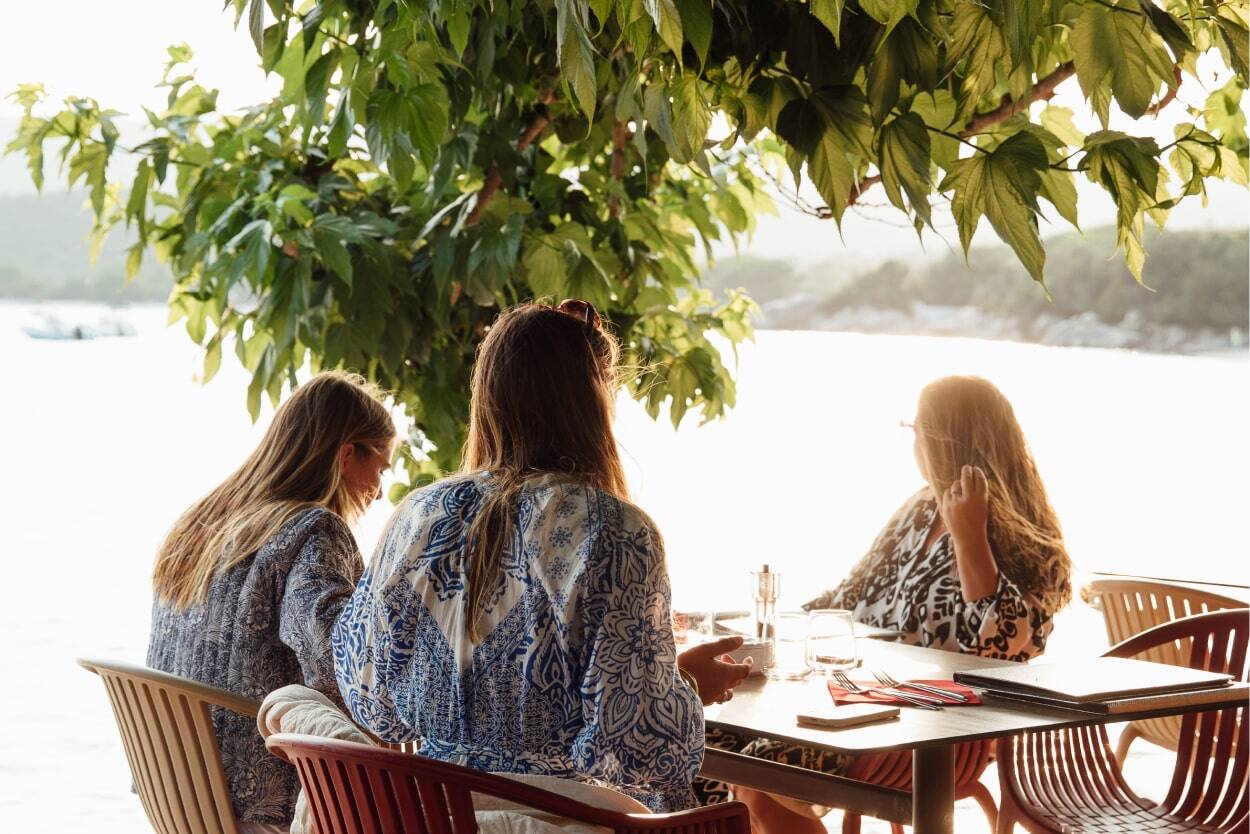 family eating by the water at a restaurant in corsica