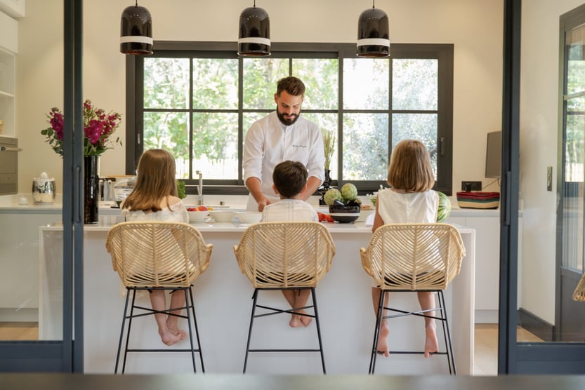a privat chef cooking a meal for a family while the children sit and watch