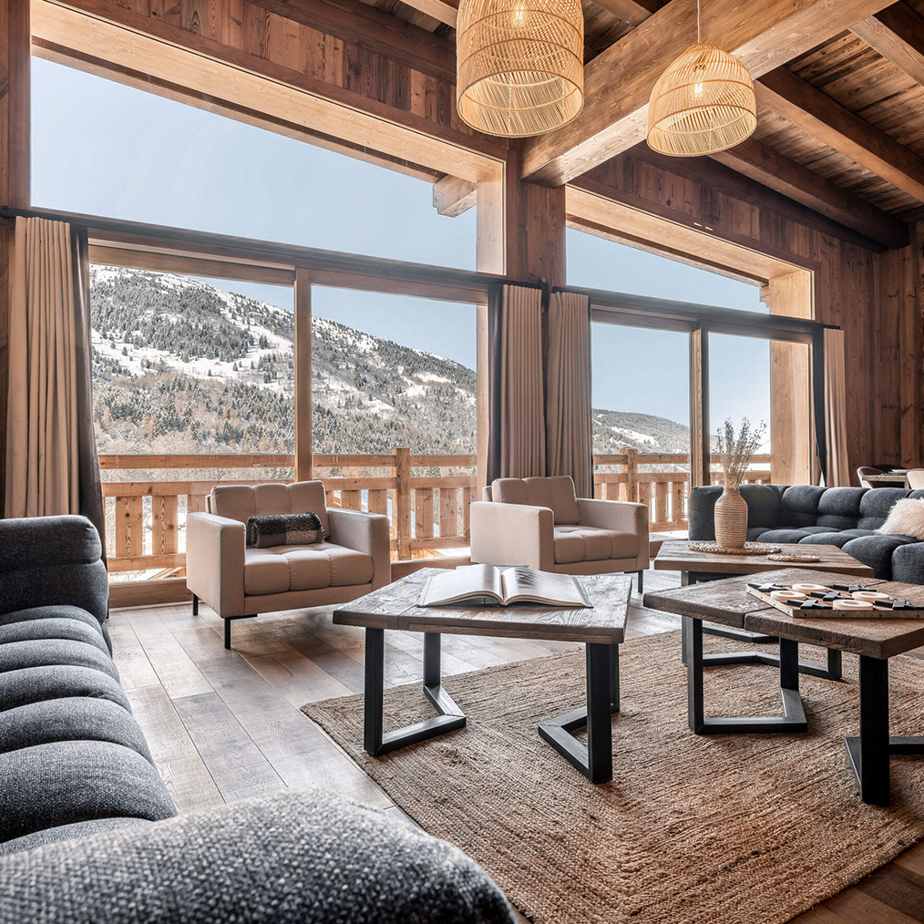 Salon du Chalet Tribu à Méribel avec de grandes baies ouvertes sur les montagnes enneigées