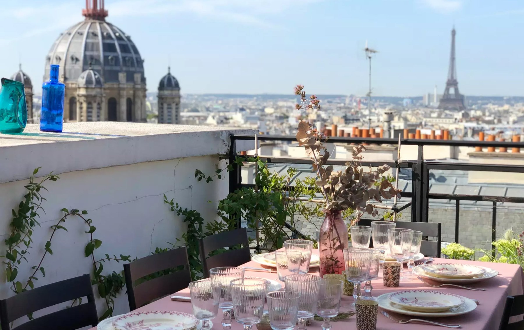 A lunch table set on a Paris rooftop terrace with views of the Eiffel Tower