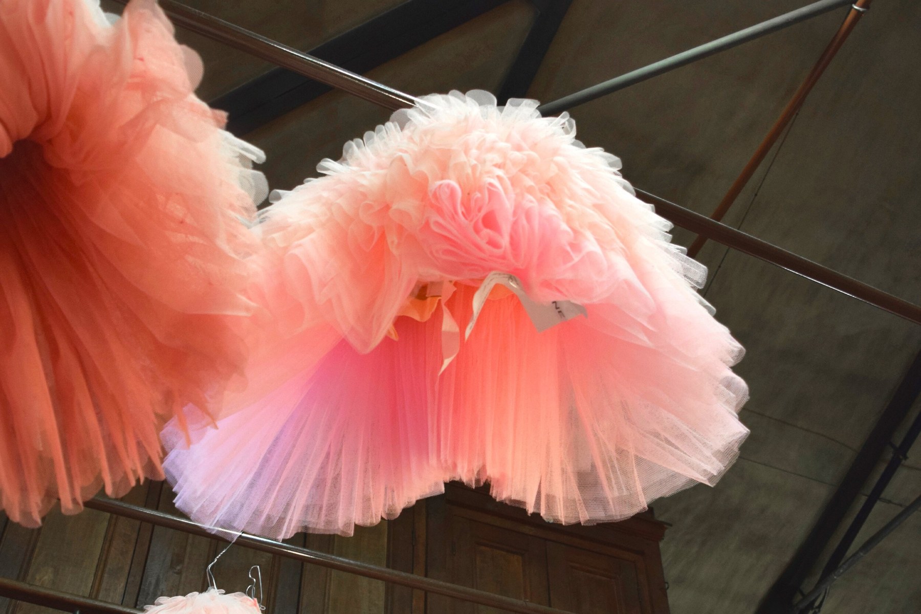A pink tulle dress hanging in a Paris fashion studio