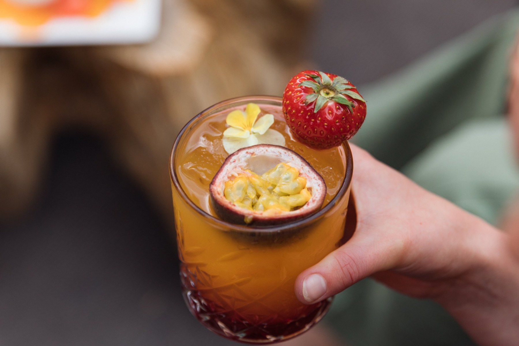 Un cocktail aux fruits de la passion et à la fraise tendu à la main