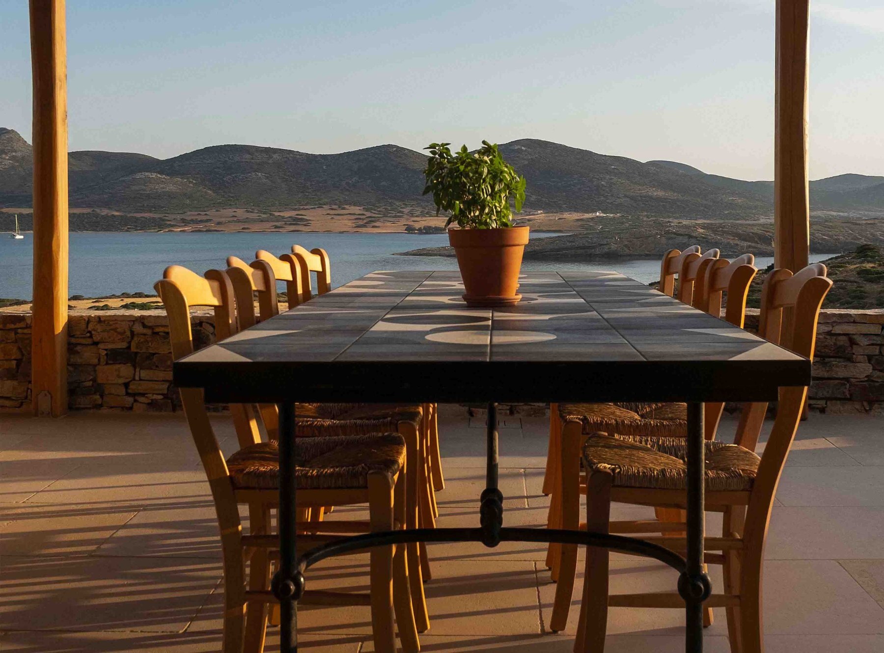 Une longue table dressée sur une terrasse face à la mer au coucher du soleil