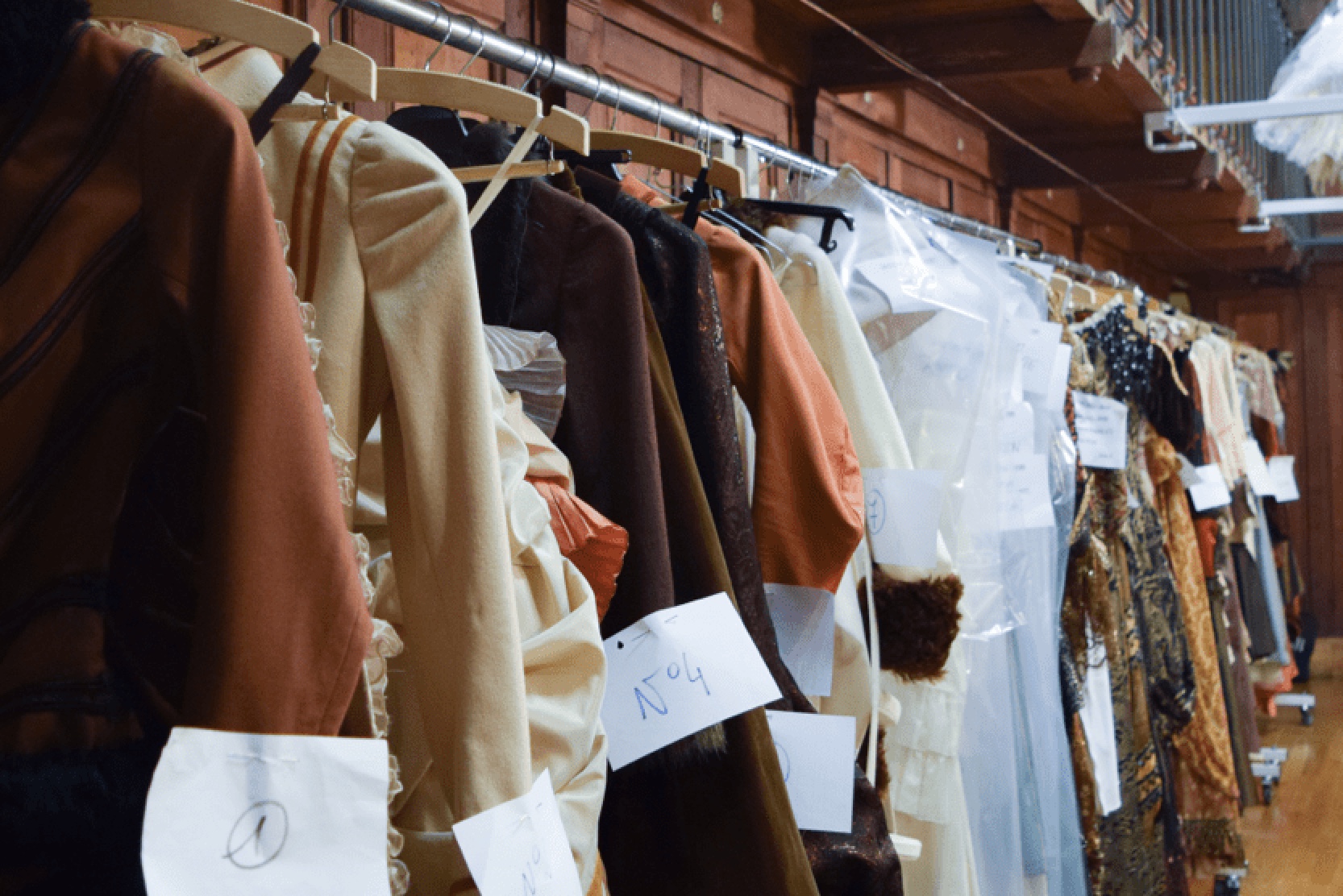 Garments with fitting notes hanging on a rail in a Paris atelier