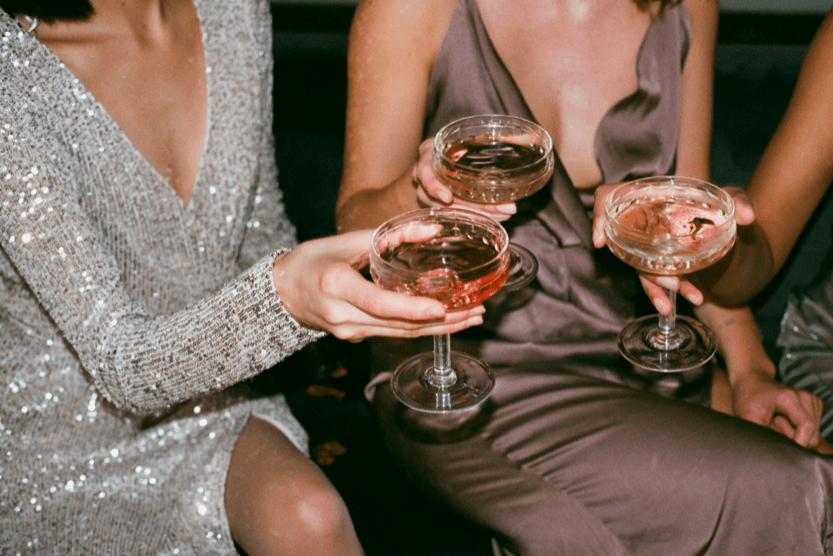trois-femmes-en-robe-de-soiree-tiennent-des-coupes-de-champagnes-et-s-appretent-a-trinquer