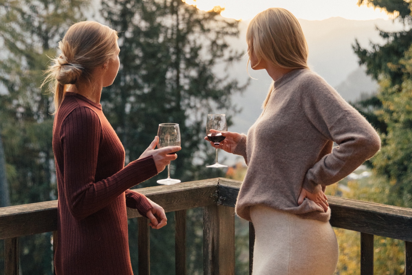 Two women with glasses of wine on a chalet balcony in Verbier