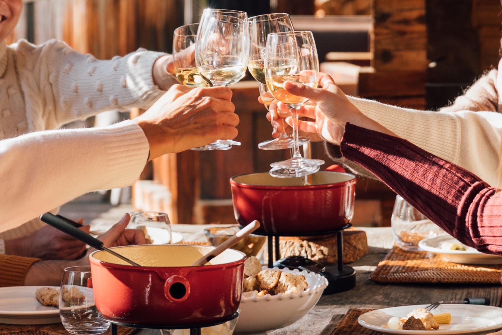 Guests raising their glasses over a raclette dinner in a Verbier chalet
