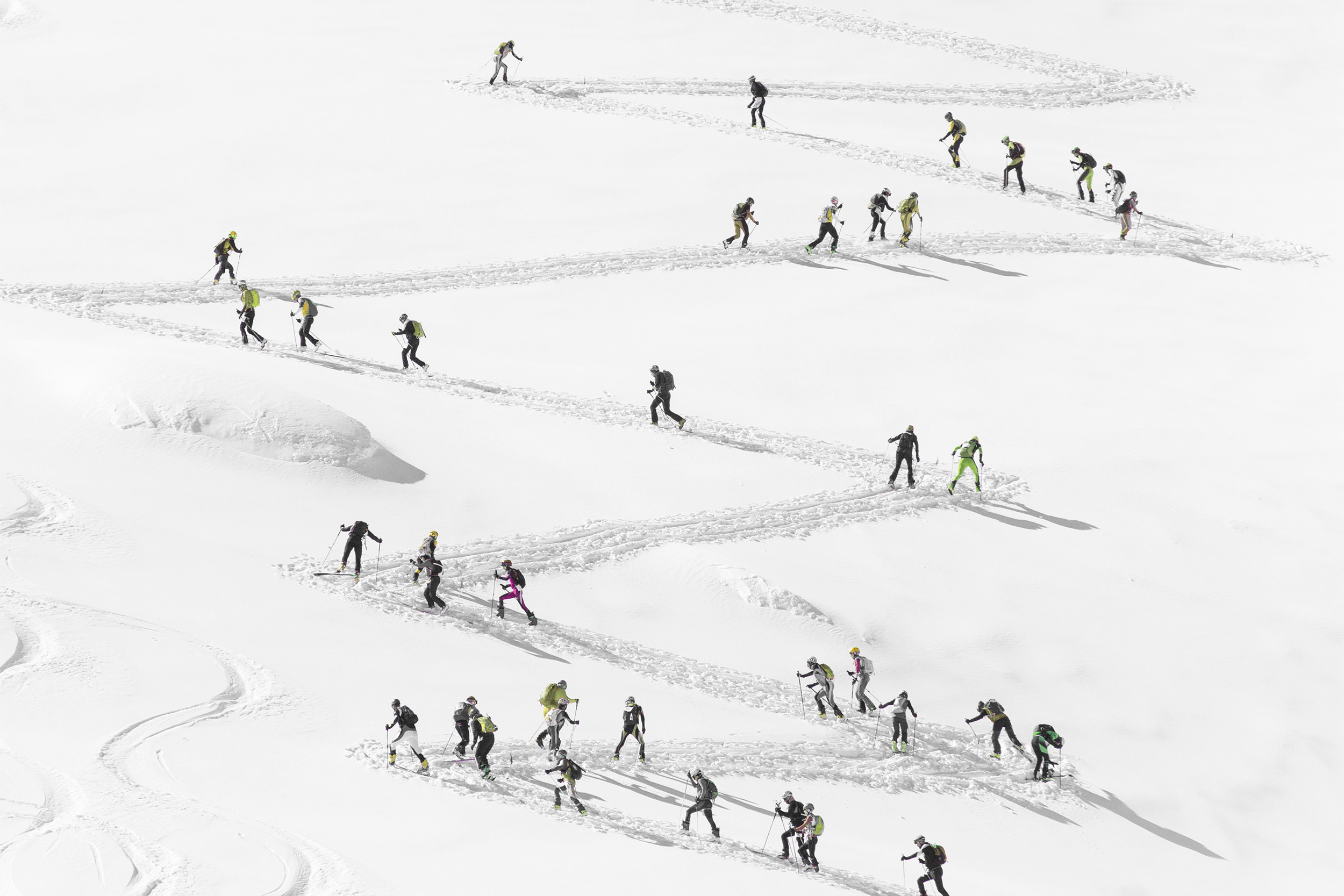 Skiers tracing a zigzag line up a snowy slope in Verbier