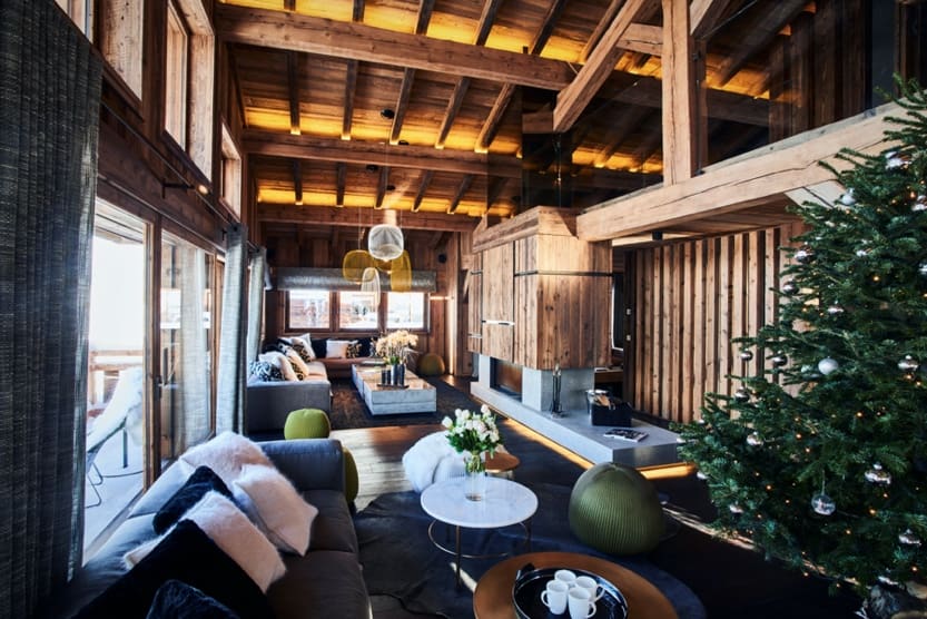 Salon du Chalet Orcia à Megève, sous une charpente en bois et face aux grandes baies vitrées