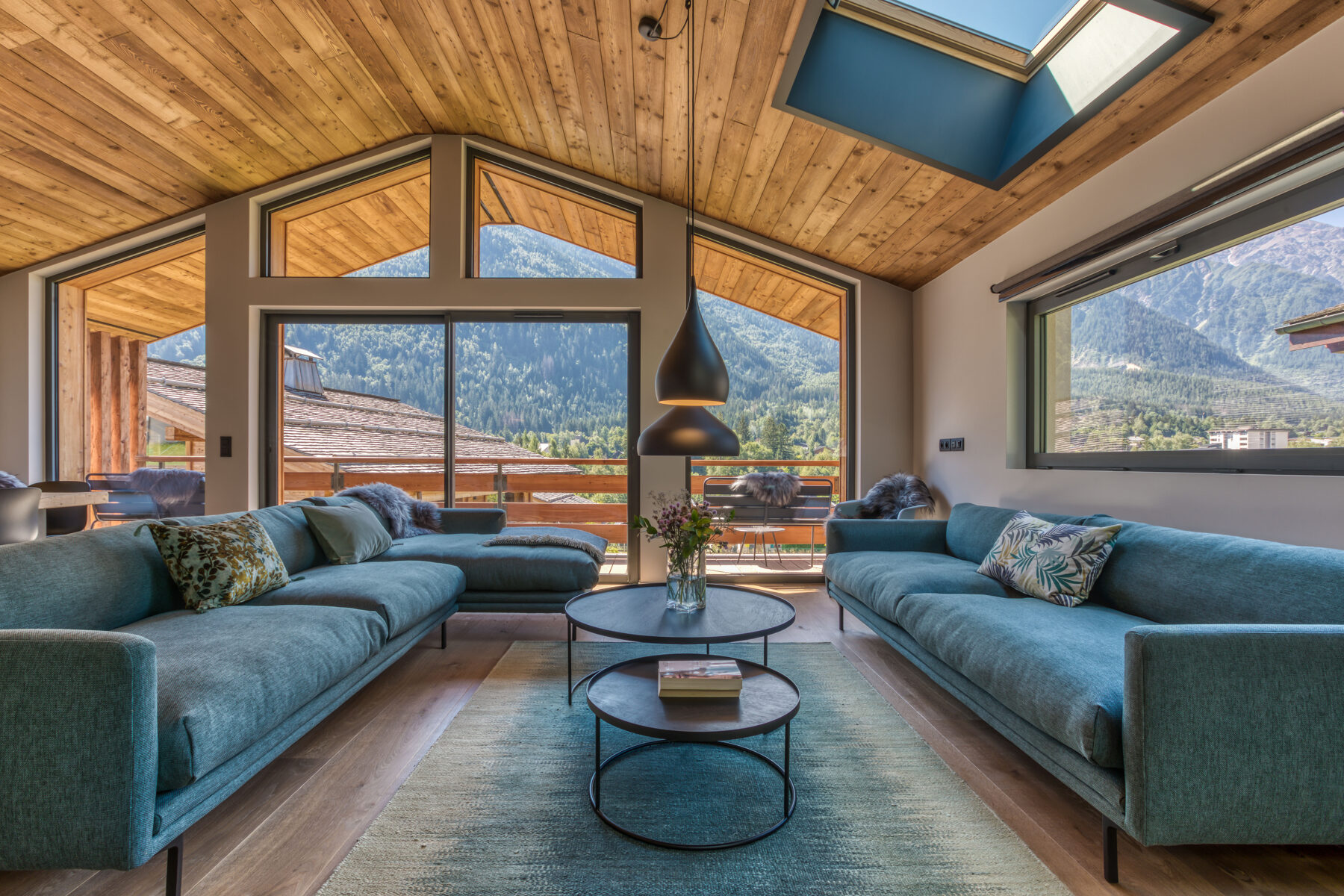 Le salon du Chalet Choucas, ses canapés et ses baies vitrées ouvertes sur les montagnes de Chamonix