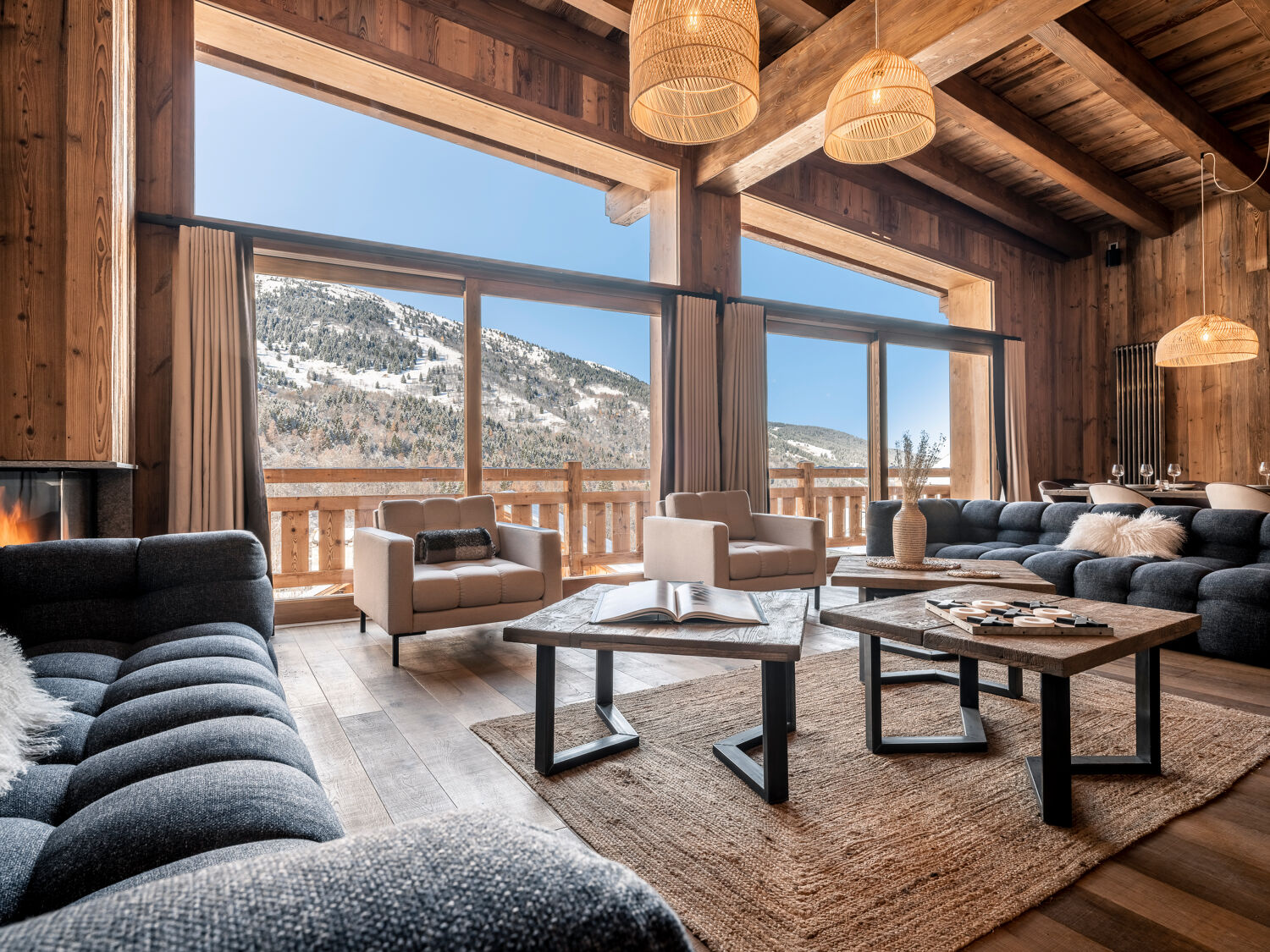 Le salon du Chalet Tribu à Méribel, poutres de bois et grandes fenêtres sur la vallée